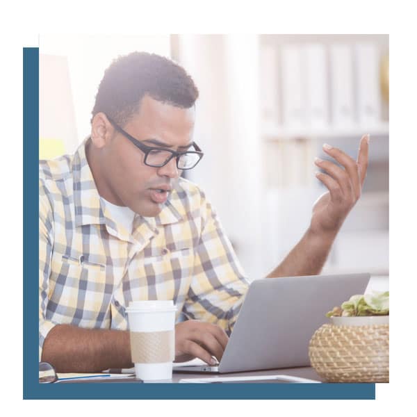 black male makes a questioning gesture while looking at a laptop